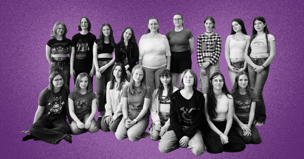 Group of about 18 young people posing together in grayscale against a purple background.